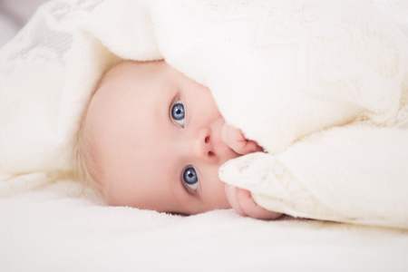 宝宝看着相机在一个白色的毯子