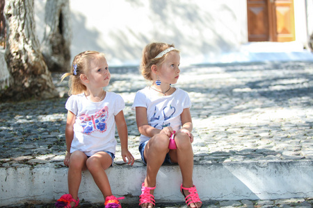 年轻迷人的女孩坐在街在老希腊村庄的商场，圣托里尼岛