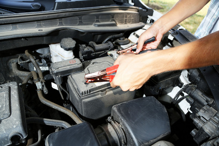 汽车修理工使用电池跳线电缆，电池充电