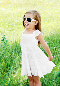 快乐可爱的小女孩在草地上的太阳镜