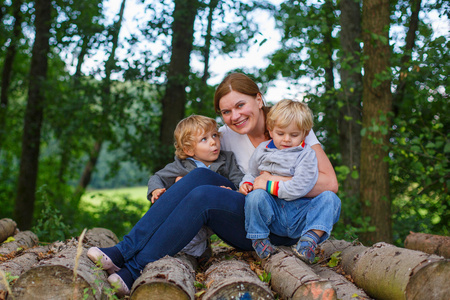 年轻的母亲和两个小男孩在夏季森林开心