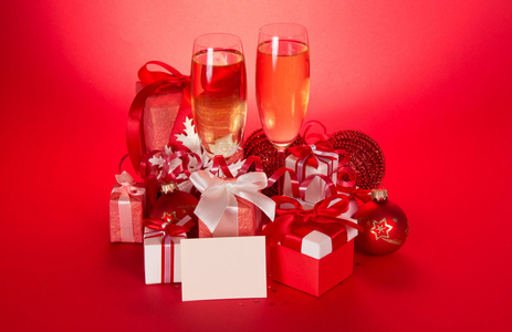葡萄酒杯香槟 礼品盒 圣诞球 雪花和空白卡上红色背景与
