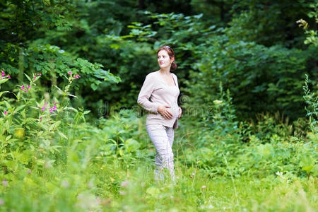 美丽的年轻孕妇在公园散步