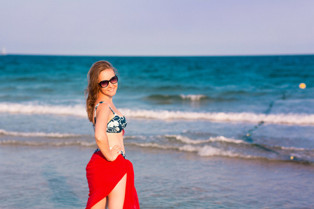 在海滩上的红色围巾的美丽女人