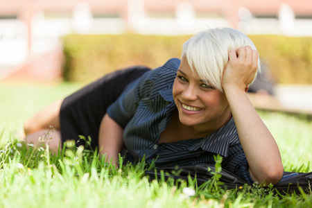 金发微笑的女人躺在草地上