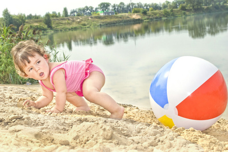 在玩沙的小女孩在湖附近的海滩上