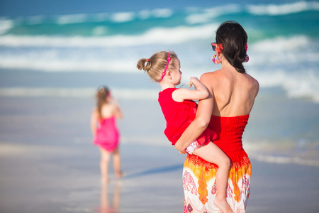 母亲和两个可爱的女儿走在异国风情的沙滩上阳光灿烂的日子