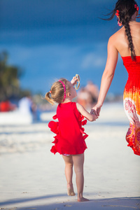 母亲和小可爱的女儿走在异国风情的沙滩上阳光灿烂的日子