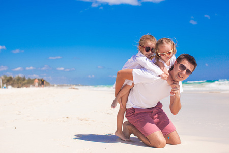 年轻快乐的爸爸和小女儿在白色的沙滩上尽情的在阳光明媚的日子