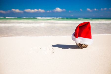 圣诞老人的帽子，在白色的沙滩上椰子