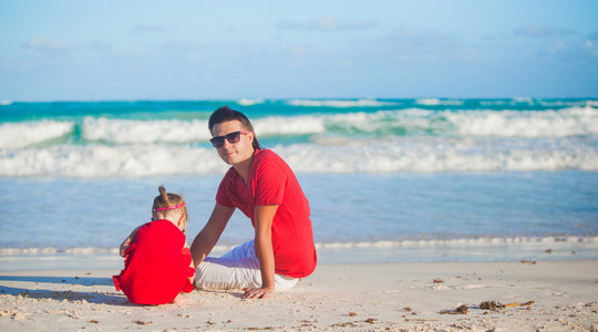 年轻的父亲和他可爱的小女儿在海边玩