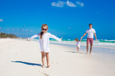 年轻的父亲和女儿在白色的沙滩上玩耍的小的可爱