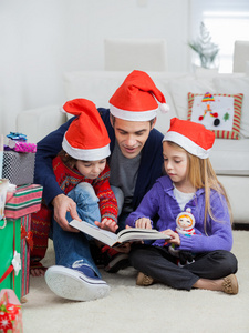 父亲和孩子在阅读本书的圣诞老人的帽子