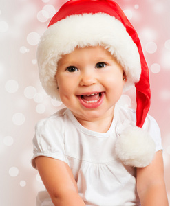 美丽有趣的婴儿在上粉红色的圣诞帽子