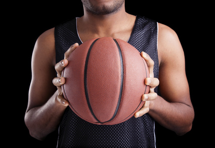 在黑暗的背景下举行一个球的篮球运动员