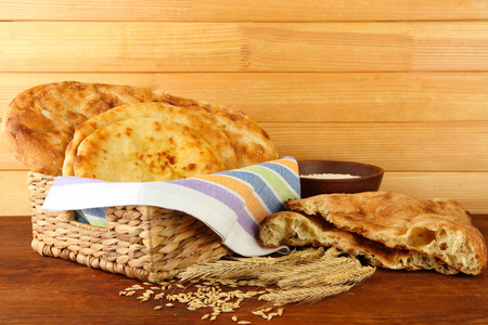皮塔饼面包在篮子里用穗状花序和面粉上木制背景表格