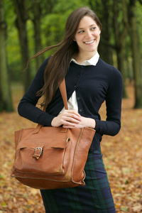 美丽的年轻女子用袋到户外散步，在秋季的一天