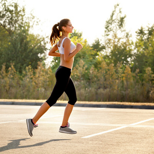 竞技赛跑者在一个公园为马拉松训练。健身的女孩