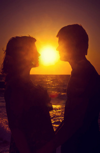 一对年轻夫妇在日落时分的爱的剪影