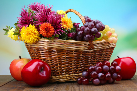 用美丽的鲜花在柳条编织的篮子和水果，在明亮的背景上的组成