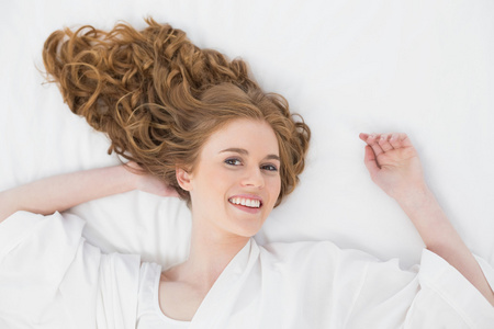 一个微笑的年轻金发女郎在床上的顶视图