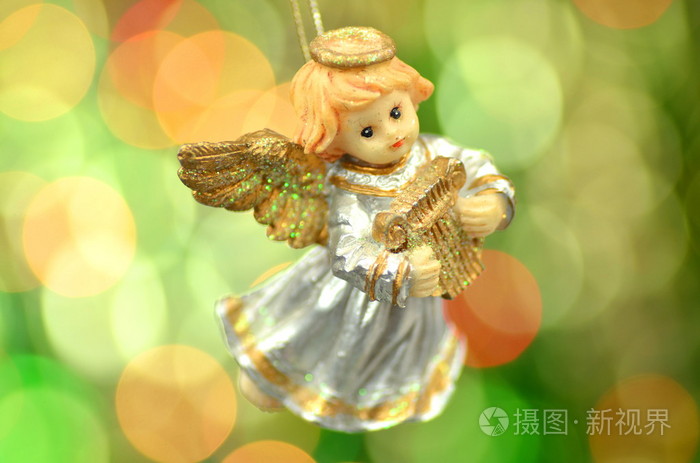 圣诞节装饰物弹奏着竖琴在景背景下的小天使图