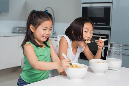 两个笑着年轻的女孩在厨房里吃谷类食品