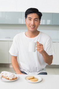 souriant jeune homme boire du caf dans la cuisine