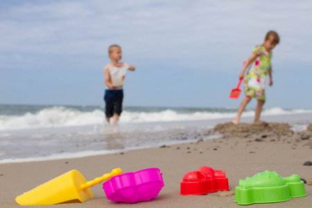 两个孩子及色彩缤纷的塑料玩具，在海滩