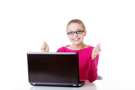 年轻快乐的女人坐在笔记本电脑前