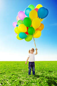小女孩控股五颜六色的气球。孩子在玩在一座绿色