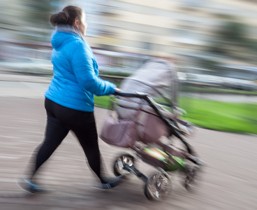 母亲带着年幼的孩子和一辆婴儿车走在街上