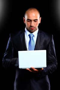 商人带着便携式计算机   在一个黑色的背景