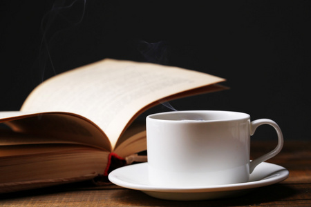 杯热咖啡，在深色背景上的桌子上的书