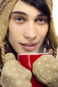 一个美丽的男人，穿着毛衣 手套 围巾和帽子，穿着冬天的寒冷和喝杯热茶的肖像
