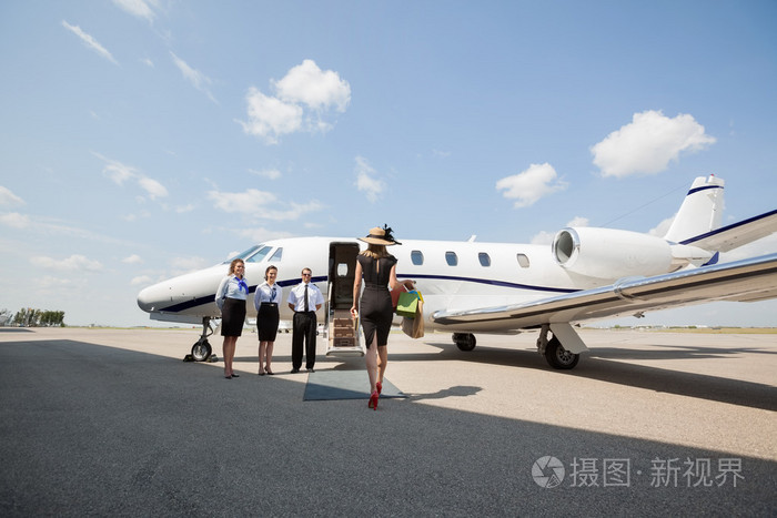 有钱的女人走向私人飞机在机场航站楼