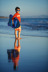 六岁的小男孩与异国风情的海滩上的冲浪板
