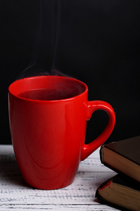 喝杯热茶与在深色背景上的桌子上的书