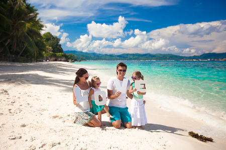 年轻漂亮的四人家庭享有在海滩上放松