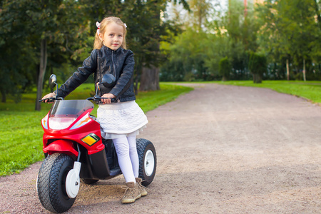 漂亮的小女孩，她的玩具摩托车户外玩乐