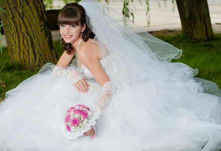 美丽的新娘穿着婚纱时用一束鲜花在性质上