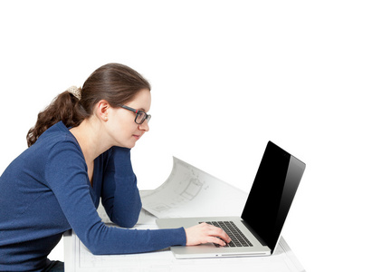 桌子后面的笔记本电脑上工作的年轻女子的照片