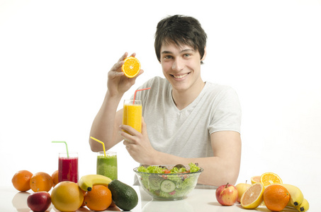快乐的人制作橙汁。活泼开朗的年轻人吃健康的沙拉 水果 橙汁和绿色奶昔