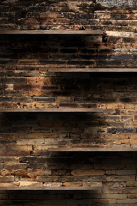 空的木书架上旧砖背景墙上，垃圾工业内部不均匀漫射照明版本