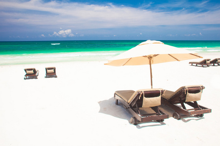多个沙滩椅和伞在沙滩上。假期