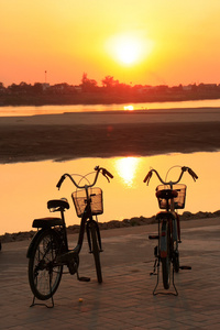 在日落时，万象，老挝湄公河河附近的剪影的自行车