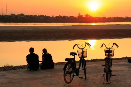 在湄公河河旁，观看日落的情侣 v
