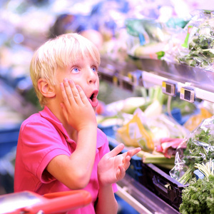 小男孩看着水果和蔬菜的价格图片