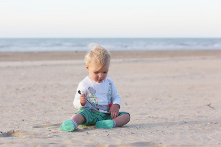 小女孩坐在玩沙的海滩上