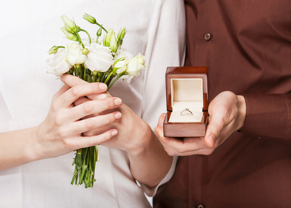 新婚夫妇拿着戒指盒和一束鲜花